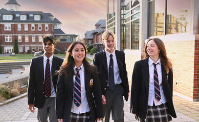 Students dressed in school uniform walk between campus buildings