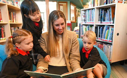 Becky Anderson reads to three Junior School students