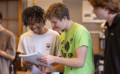 Two students look over a music sheet with smiles as they get ready for a theatre rehearsal 