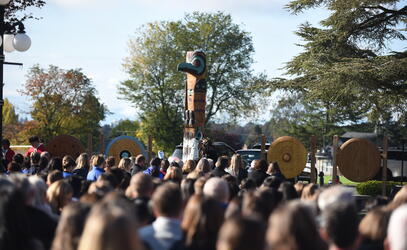 A large crowd of students look on to the Welcome Pole unveiled at the Richmond Road campus. 