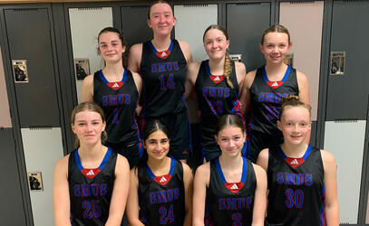 8 players in basketball uniform stand in front of some lockers