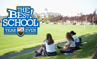 Looking behind three SMUS students sitting on the grass looking out over campus 
