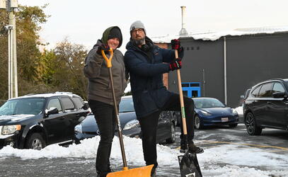 Cathy Beglau and Morgan Besant pose in the middle of clearing snow on the pathway