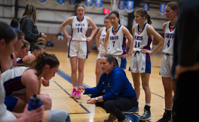 Senior Girls basketball coach Lindsay Brooke talks to the team in a huddle at a break. 