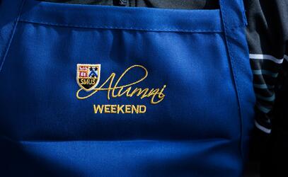 Alumni Weekend text is embroidered on to an apron worn by a Board of Governor for the annual pancake breakfast