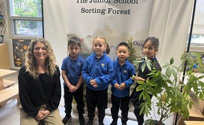 Junior Kindergarten students stand by the banner highlighting the sorting forest. 