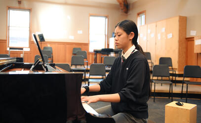 Graduating student Emily Wu plays the piano in the choir room. 