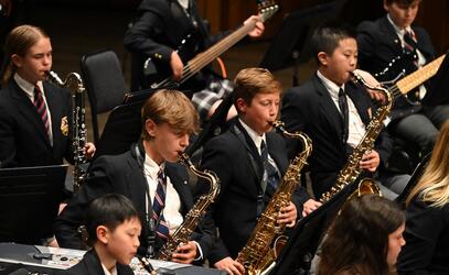 Saxophone players in the Middle School band concentrate while performing on stage. 