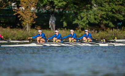 The Women's Youth Coxed Four pull hard on the water at the Head of the Charles rowing regatta.