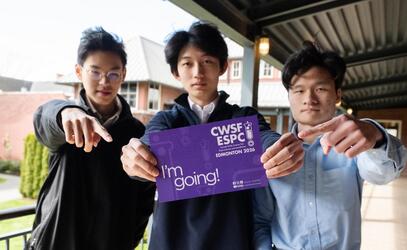 Senior School students George, Ruibo and Alvin pose with a postcard that says they are going to the national science fair.