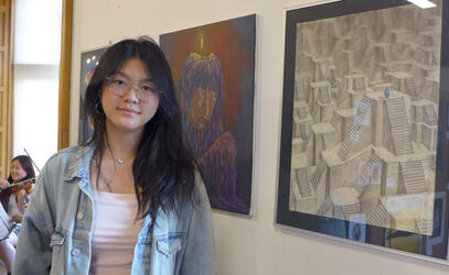SMUS student Yina Ding '27 stands next to her artwork