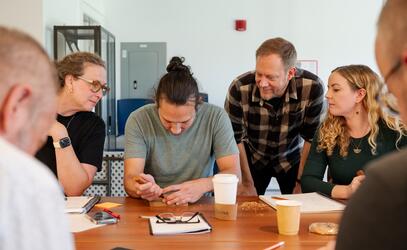 Staff Art teachers look on as Indigenous artist Dylan Thomas carves a cedar plank