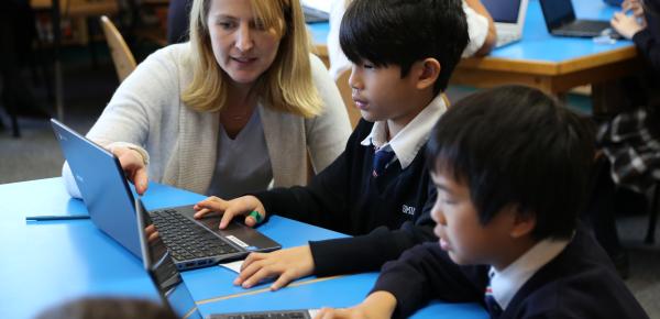 Teacher and Junior School students working on a laptop