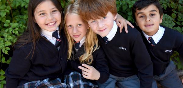 Junior School student friends grouped by a hedge