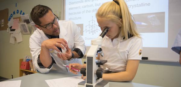 Teacher instructing Middle School student with a microscope