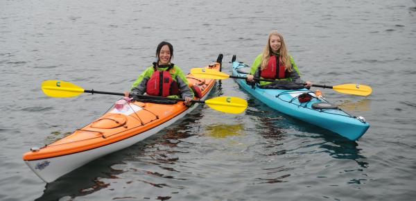 Two students paddling in ocean kayaks