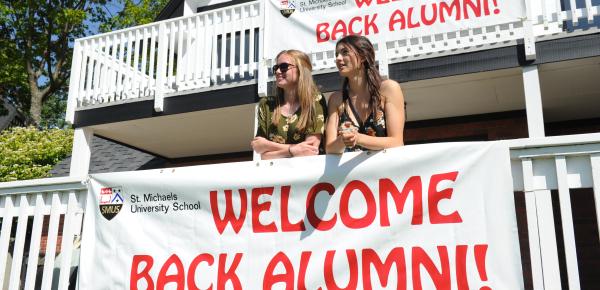 Alumni hanging out at the Wenman Pavilion with "welcome back" banners