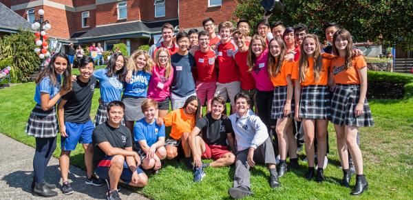Large group of boarding students in their house shirts in front of houses