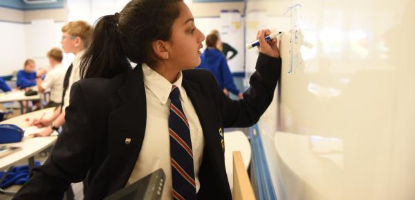 Middle School student doing math on the classroom whiteboard