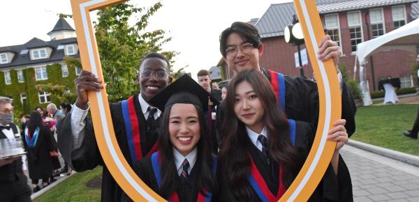 A group of Grade 12 students pose with the SMUS crest after graduation