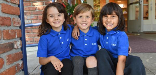 A group of Junior Kindergarten students smile on the steps of the Junior School