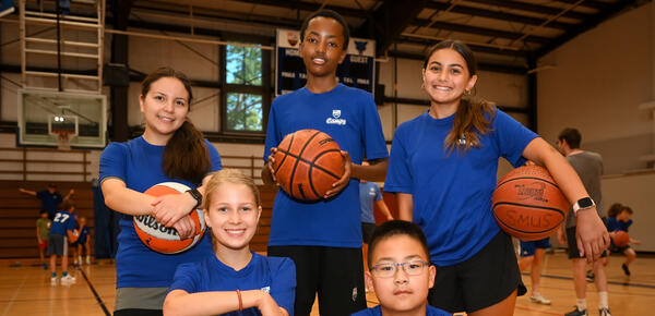 Group of five players taking a staged photo holding Basketballs 