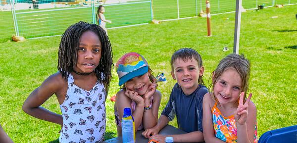 Four day campers smiling at the camera with a watertight happening around them