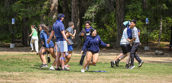Campers playing a game of tag with SMUS Camps staff on a field at Camp Barnard 