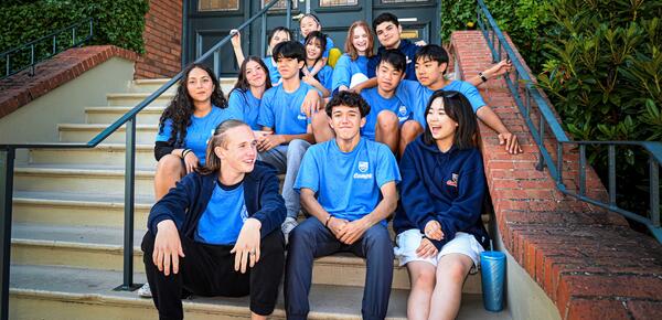 Coed group of campers sitting outside the SMUS school house in Camps t-shirts smiling