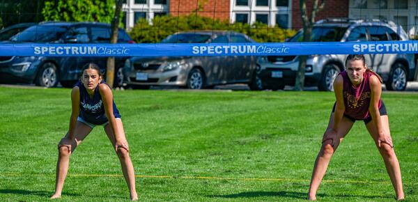 Two female campers on volleyball court guarding ready to block the ball