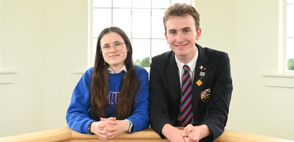 A photo of head prefects Chelsea Lee and Will Cuddihy leaning over a banister up in the sun lit bell tower of the SMUS School House Building. 