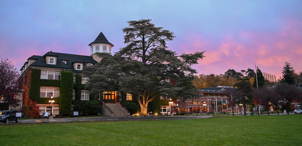 An early morning photo of the School House Building with a dark but colourful sky in the background. 
