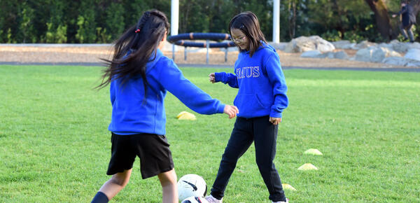 Two Junior School students practice soccer