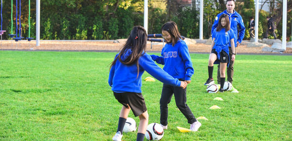 Junior School students practice soccer on the field 