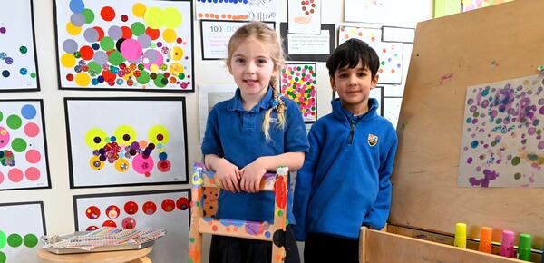 Junior Kindergarten students pose with their colourful dot artwork. 