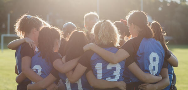 SMUS Rugby Team embrace in a team huddle as the sun beams down. 
