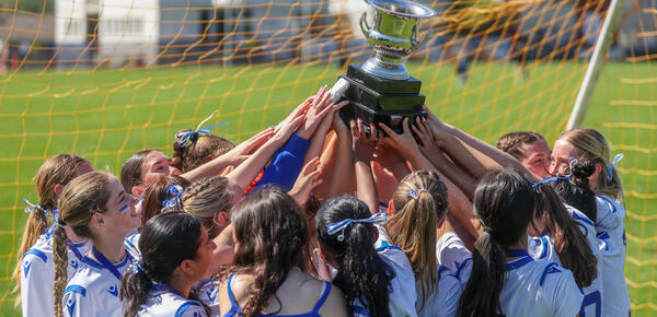 Senior Girls Soccer Team all hoist the ISAA Trophy together