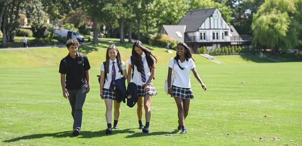 Four Senior School students walk across the school field. 