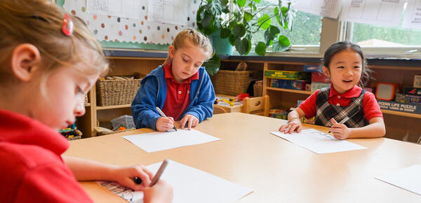 Kindergarten students busy drawing at a table