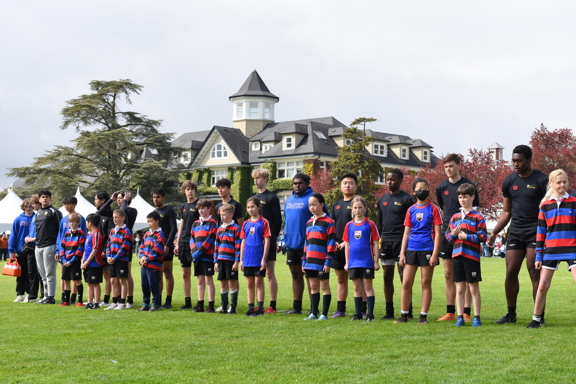 Junior School student rugby players stand alongside Senior School rugby players during Alumni Weekend