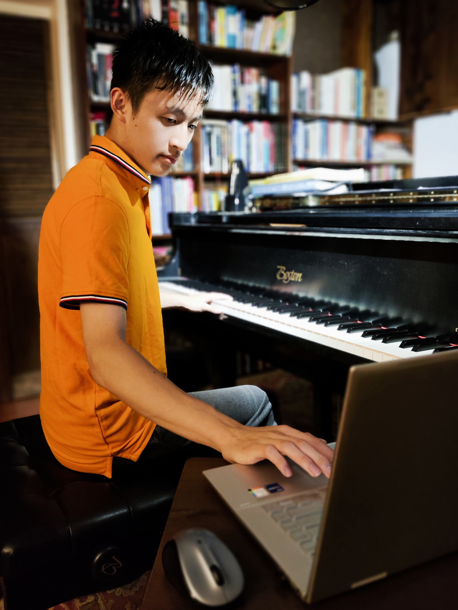 A photo of Houtian Zhong composing at his piano