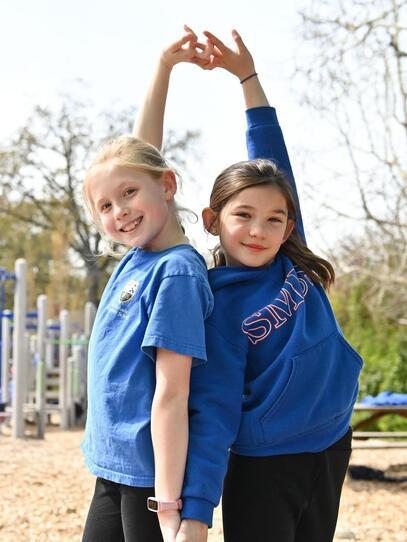Grade 4 students hold hands and pose on the playground