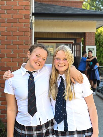 Two Grade 8 students smile outside the Middle School building