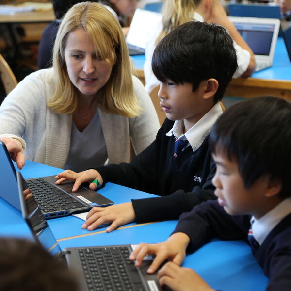 Teacher and Junior School students working on a laptop