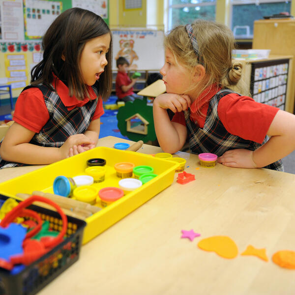 Two Kindergarten students in conversation over Playdoh