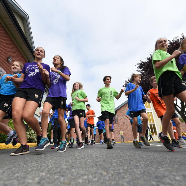 Many Middle School students in house t-shirts doing a run