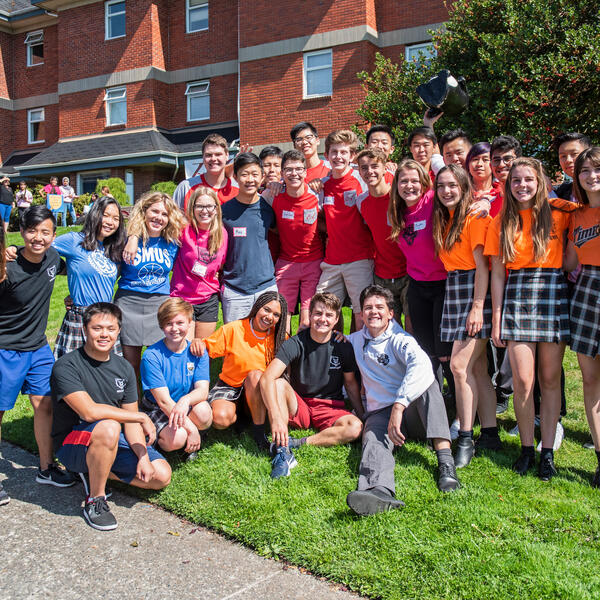 Large group of boarding students in their house shirts in front of houses