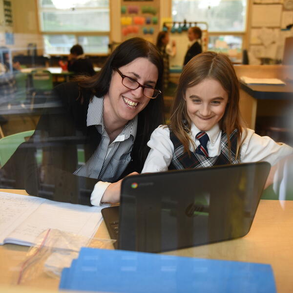 Junior School teacher and student working with a laptop