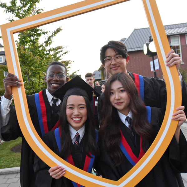 A group of Grade 12 students pose with the SMUS crest after graduation