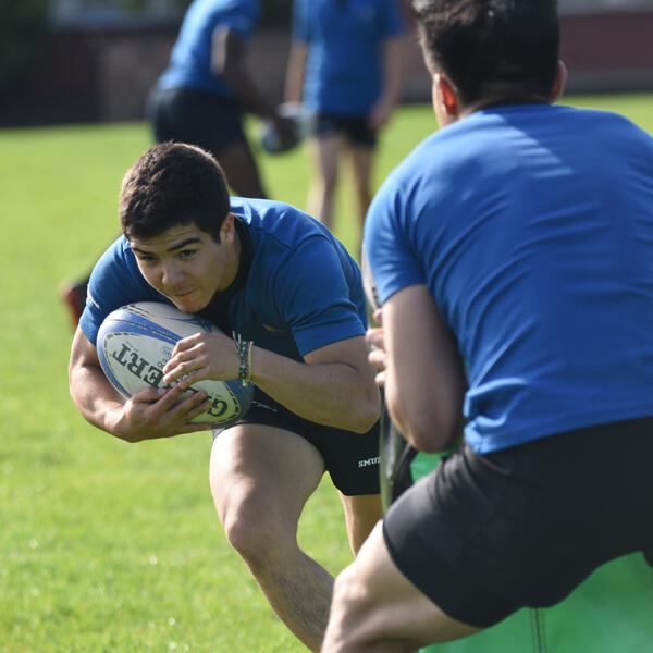 A rugby player practices going into a tackle